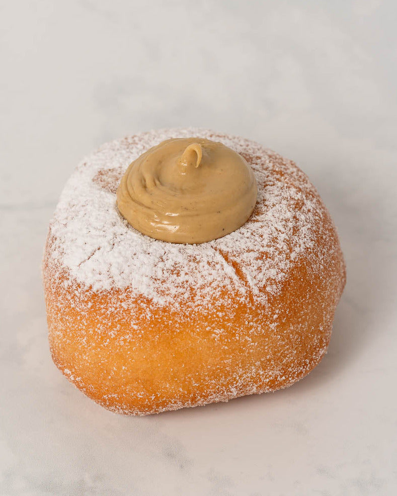 Donut with pistachio filling and powdered sugar on a light gray background
